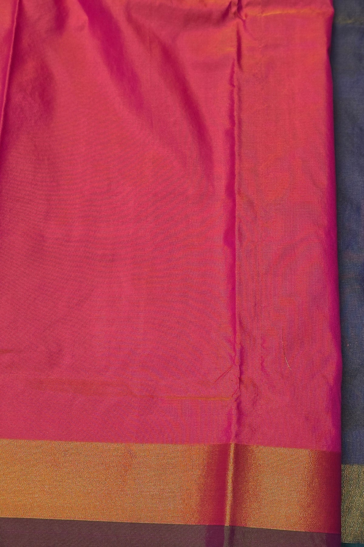 Close-up of a pink fabric with a gold border on a dark background
