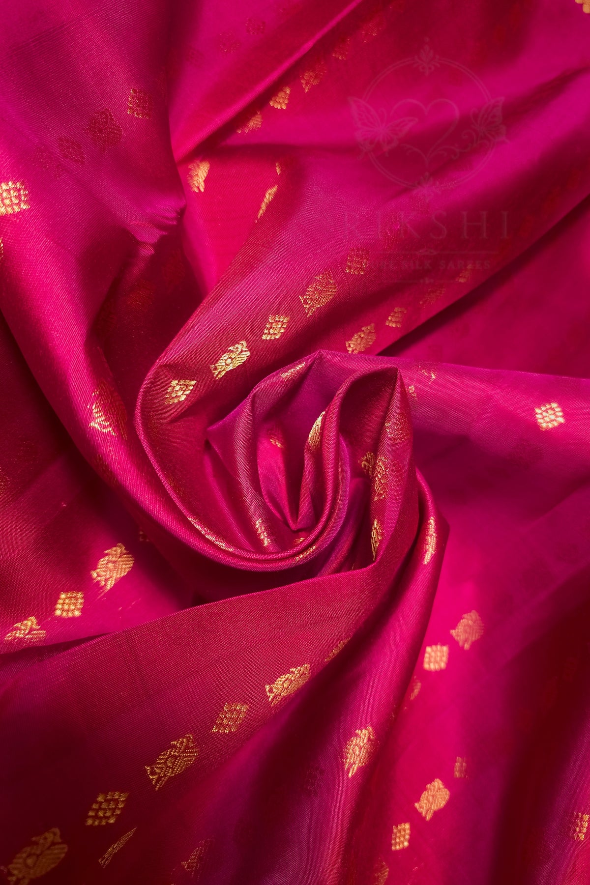 A close-up of draped magenta pink fabric with small metallic gold woven motifs and a subtle sheen, arranged in a spiral fold.