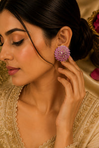 Woman wearing a pink floral earring with a gold and pink background