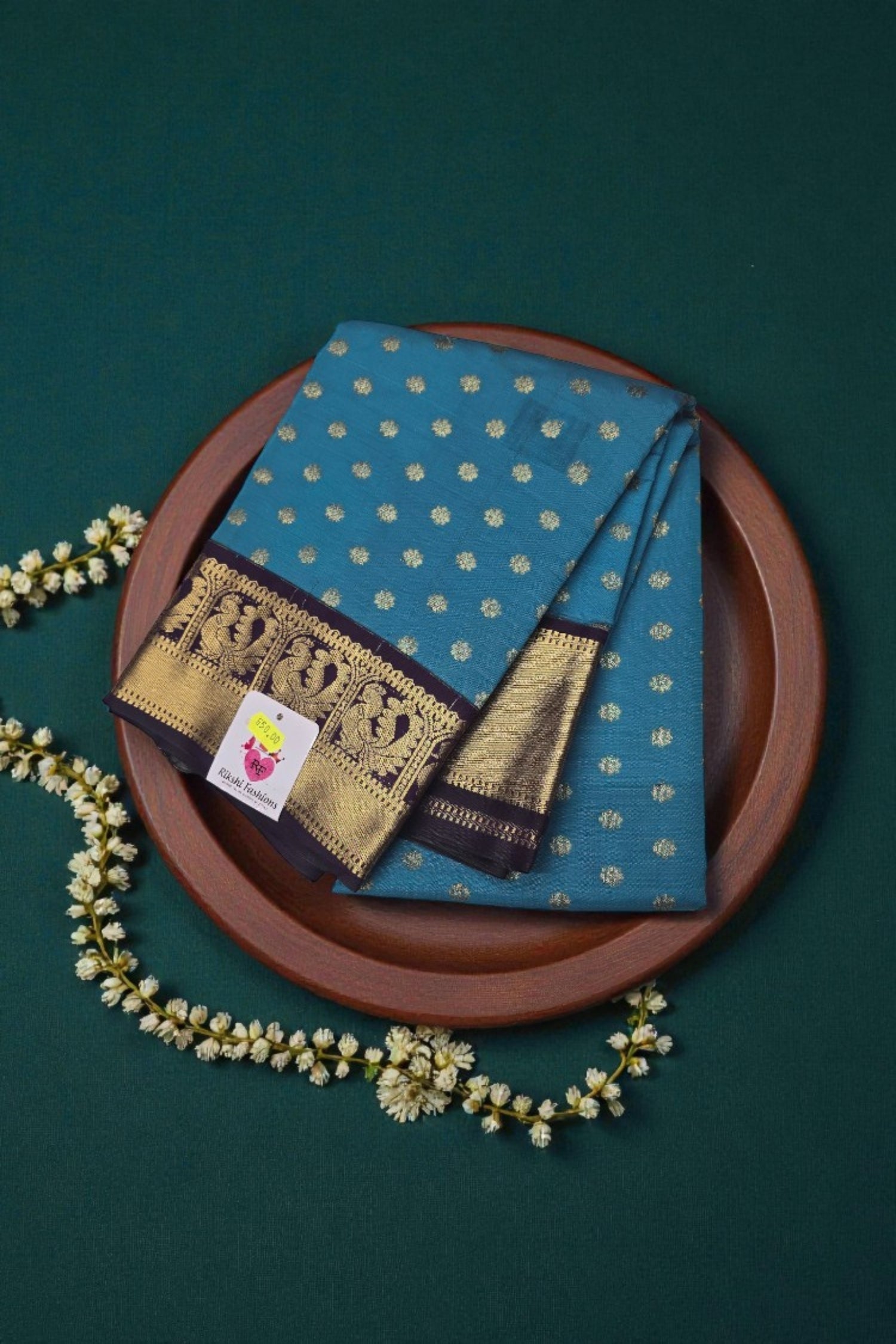 Blue saree with gold patterns on a wooden plate against a green background