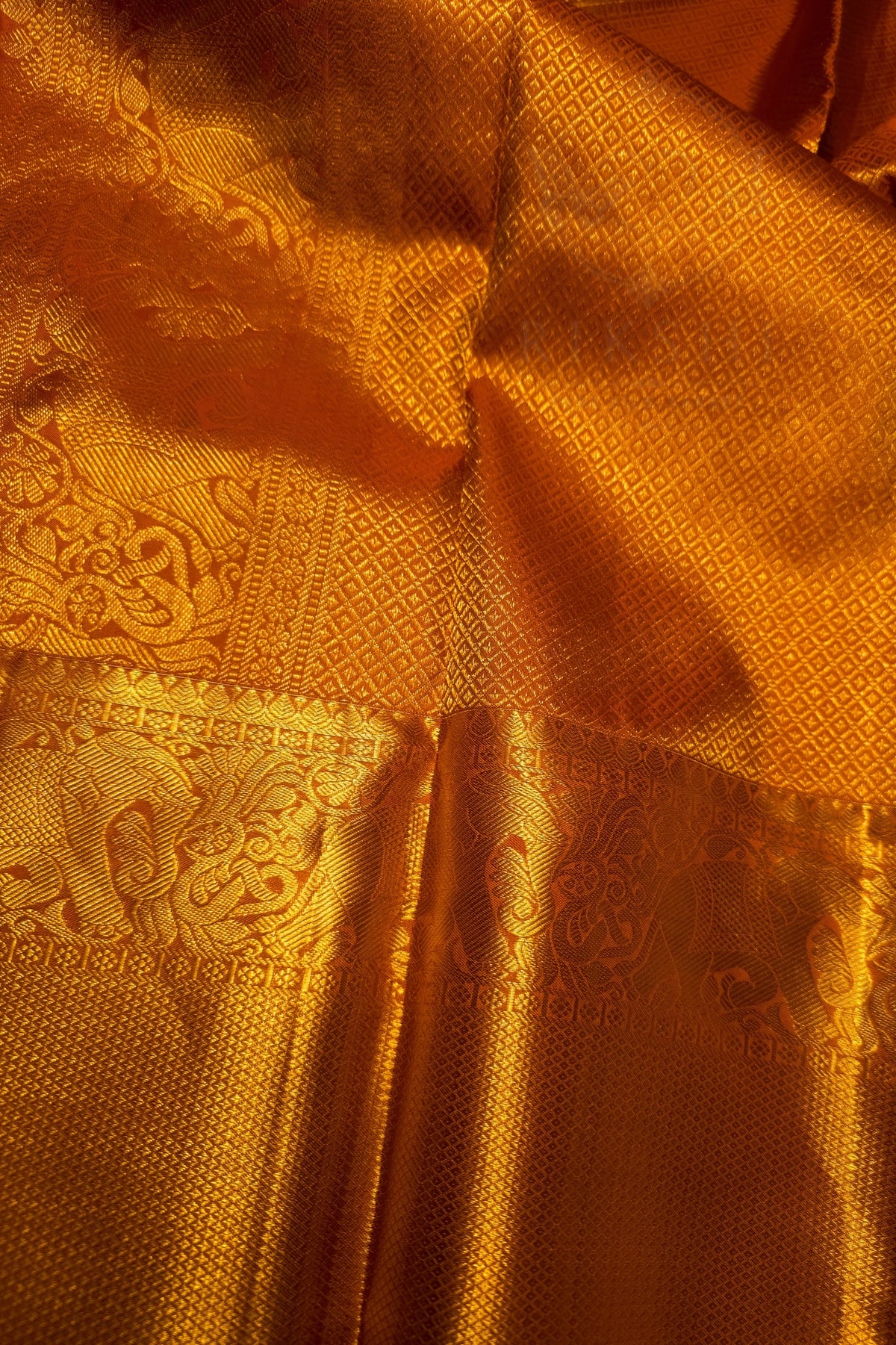 Orange Gold Floral Brocade Woven Fabric showing intricate floral patterns and a shimmering zari border.