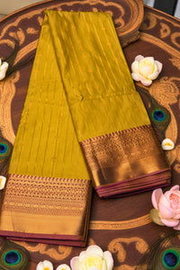 Green saree with gold border on a decorative wooden surface with peacock feathers and flowers.