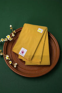 Mustard yellow napkins on a brown woven tray with a green background