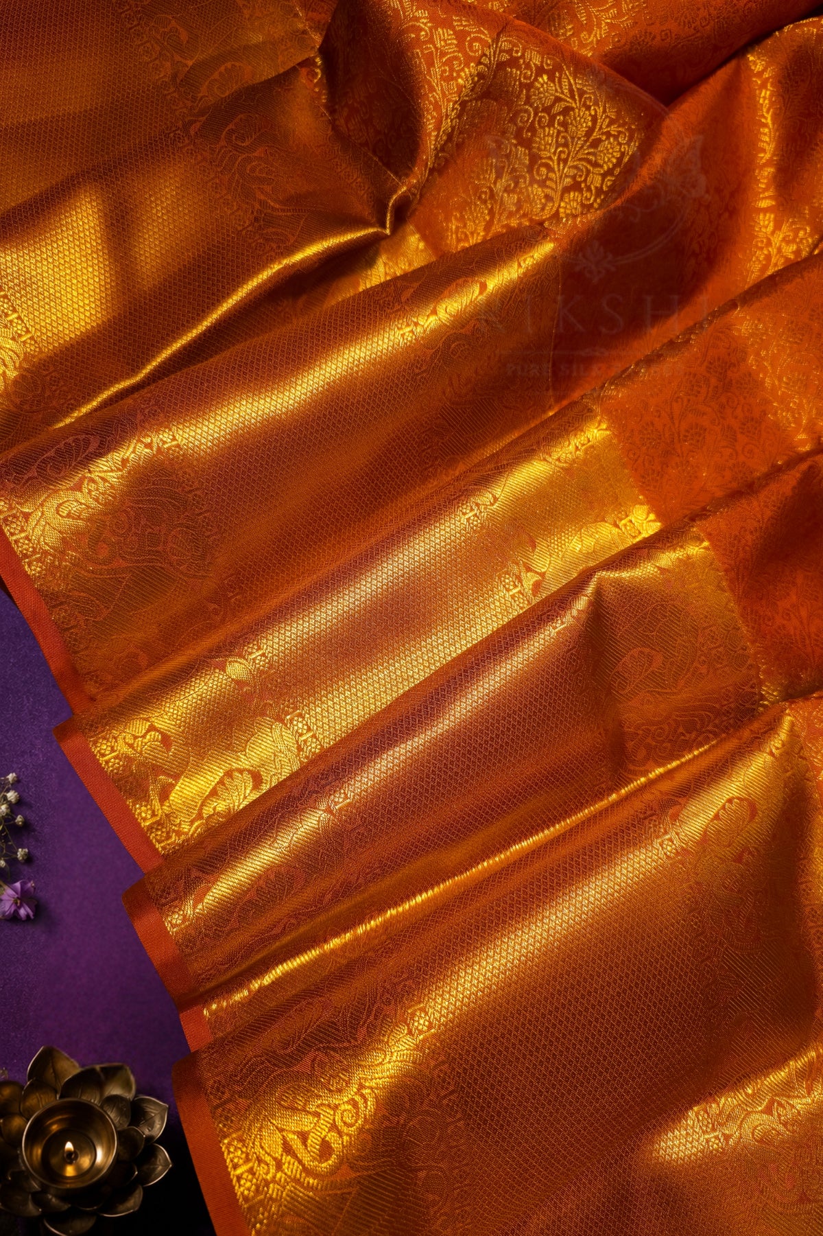 Orange Gold Floral Brocade Woven Fabric displaying intricate floral patterns and a shimmering zari border.