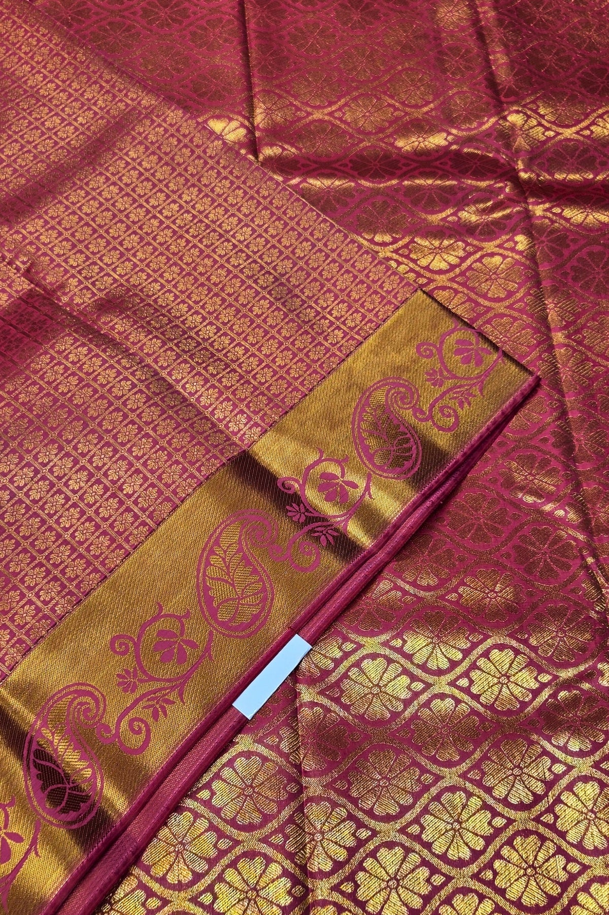 Close-up of a maroon and gold traditional fabric with intricate patterns