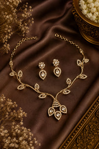 Gold jewelry set with necklace and earrings on a brown fabric background
