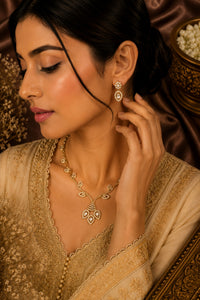 Woman wearing gold jewelry including earrings and a necklace, with a decorative background.