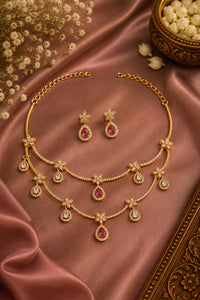 Gold necklace and earrings set on a satin surface with flowers