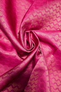 A close-up of bright pink fabric with a metallic gold woven floral pattern, arranged in a spiral drape.