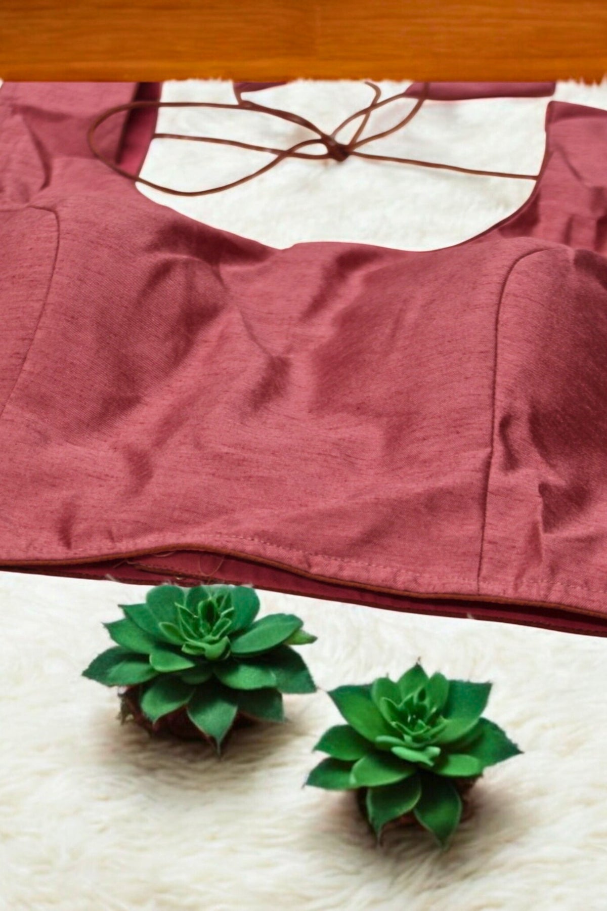 Red bra on a white surface with two green succulents in front