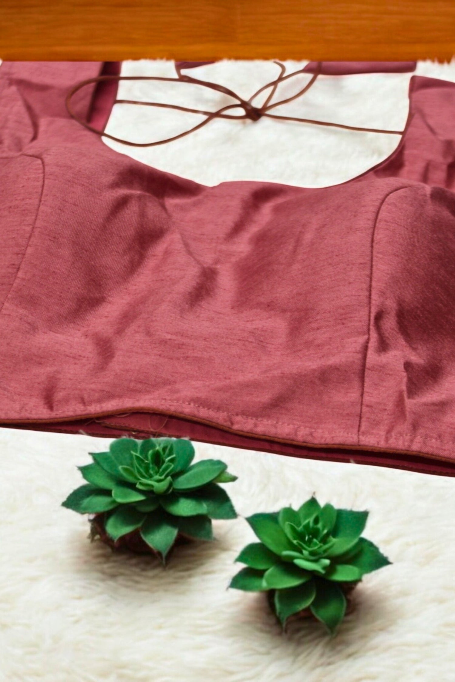 Red bra on a white surface with two green succulents in front