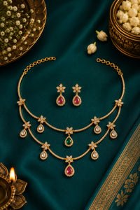 Gold necklace and earrings with gemstones on a dark green fabric background
