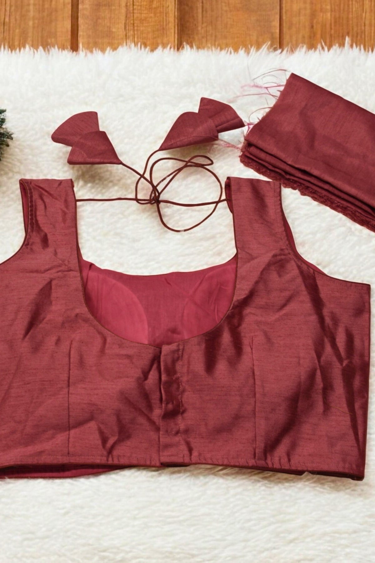 Maroon sports bra and shorts set on a textured surface with a wooden background.