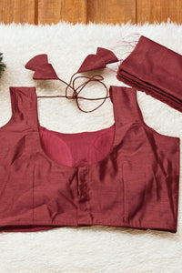 Maroon sports bra and shorts set on a textured surface with a wooden background.
