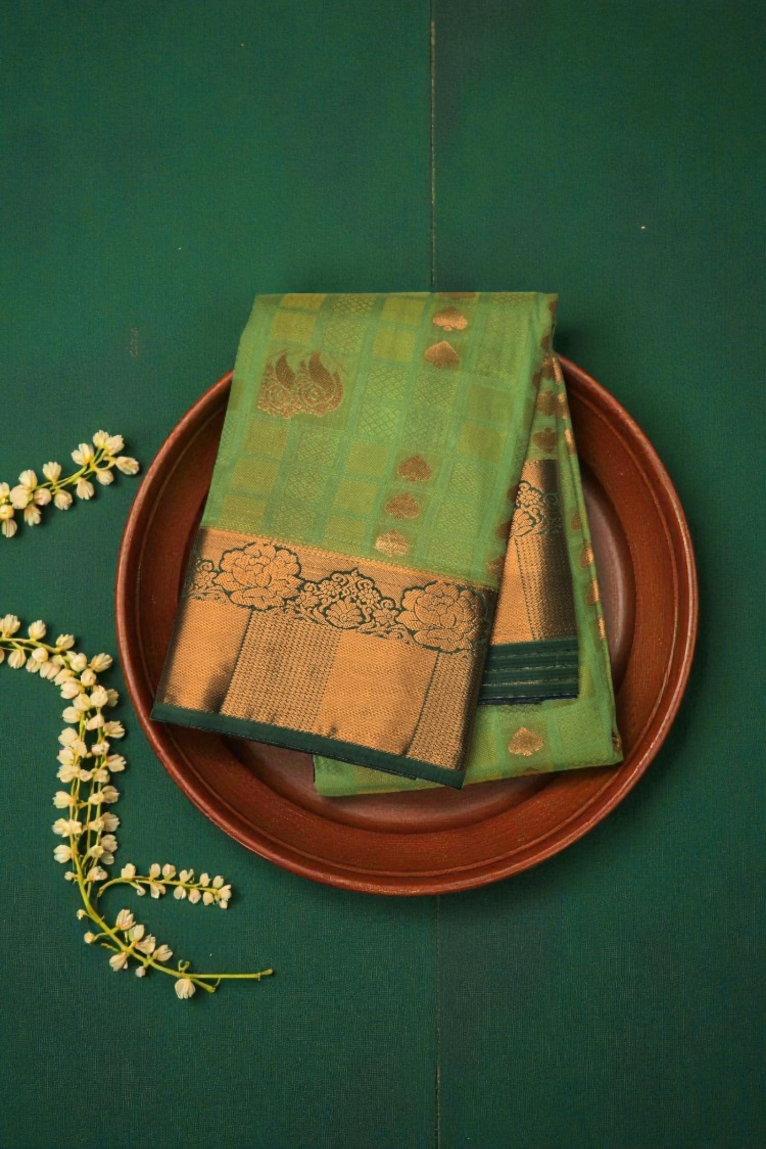 Green and gold traditional fabric on a brown plate with a green background