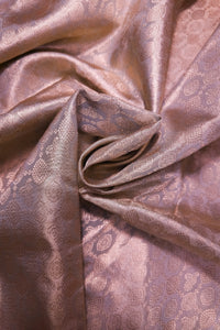 A close-up of draped satin fabric in a dusty mauve-purple color with a woven floral jacquard pattern.