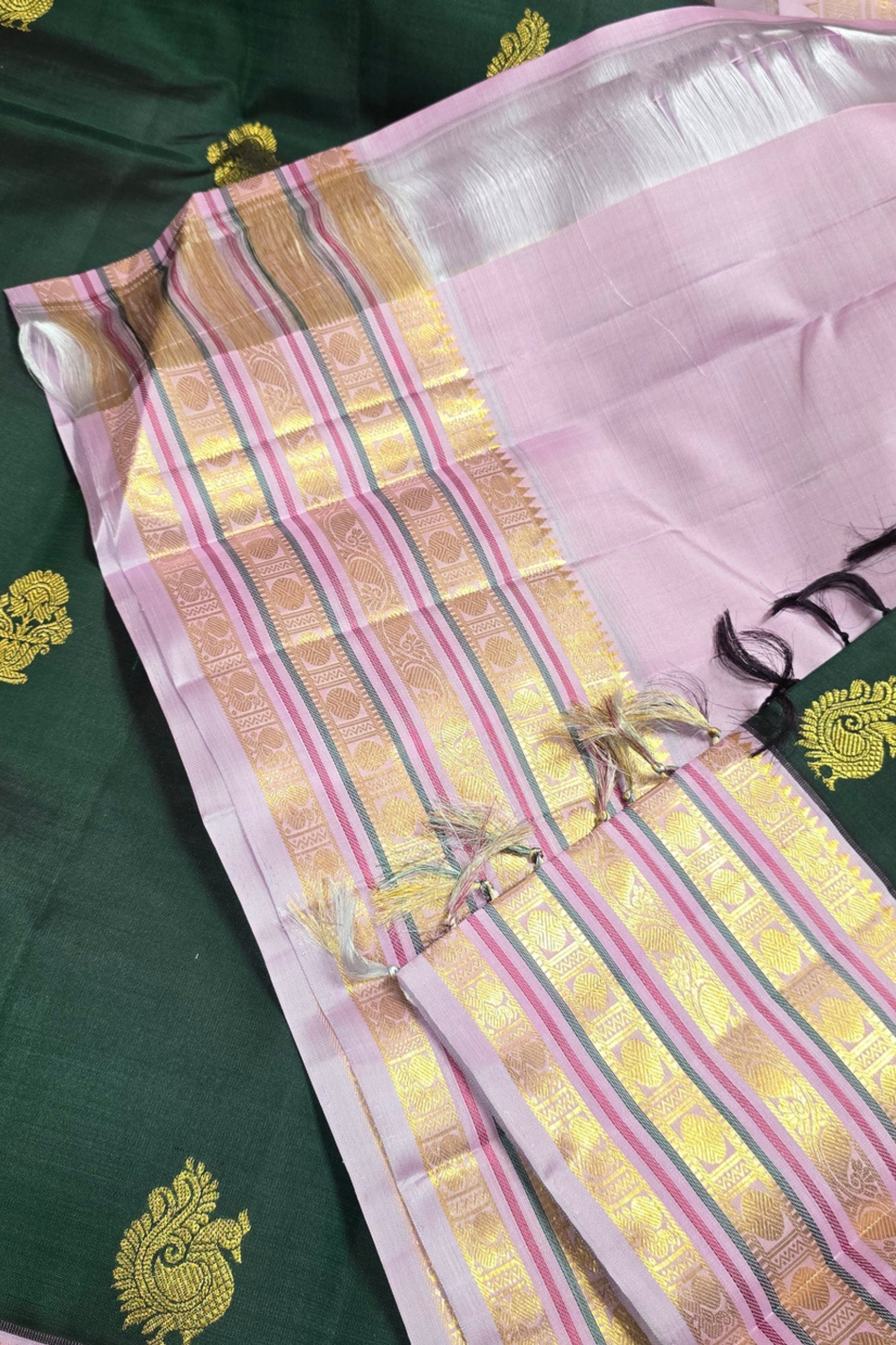 Traditional saree with pink and gold border on a green background