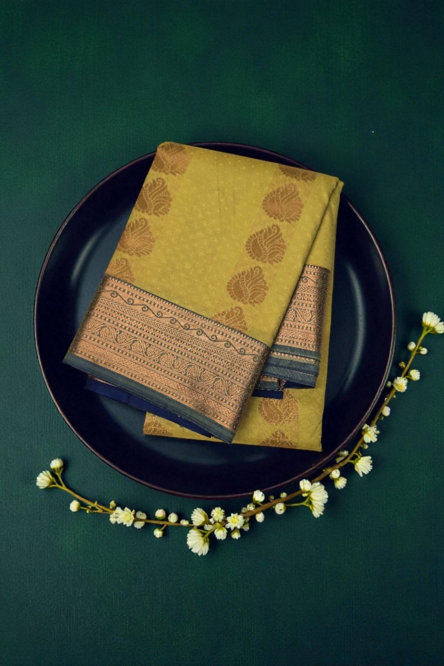 Green patterned napkin on a dark plate with white flowers on a green background