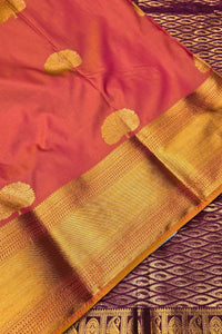 Pink saree with gold border and patterns on a textured surface