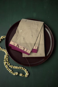 Gray saree with purple border on a dark green background