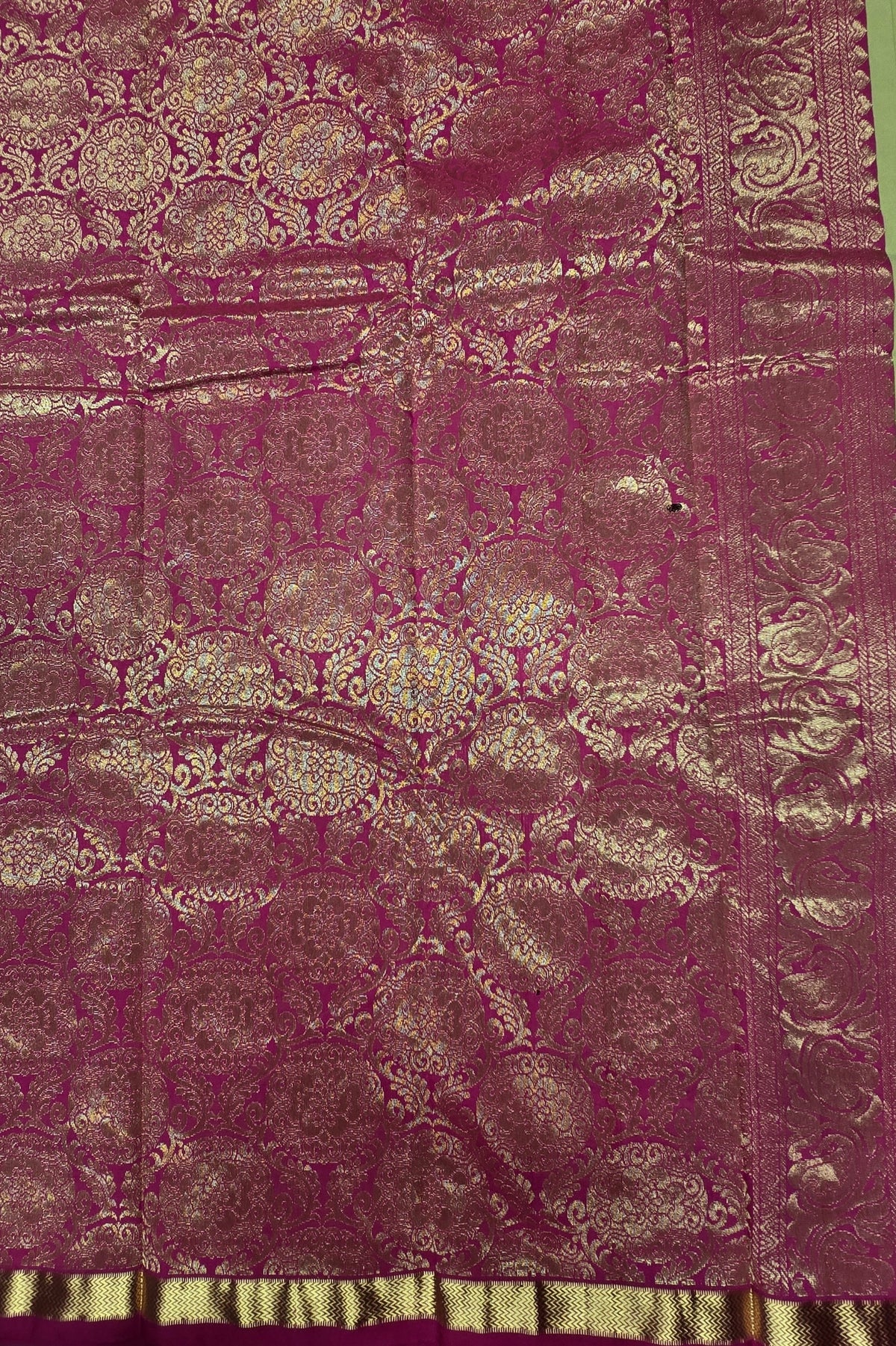 Close-up of a patterned fabric with intricate designs on a green background