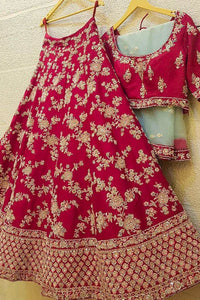 Red traditional outfit with floral patterns on a wooden hanger against a light background