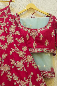 Red embroidered traditional outfit on a hanger against a beige wall.