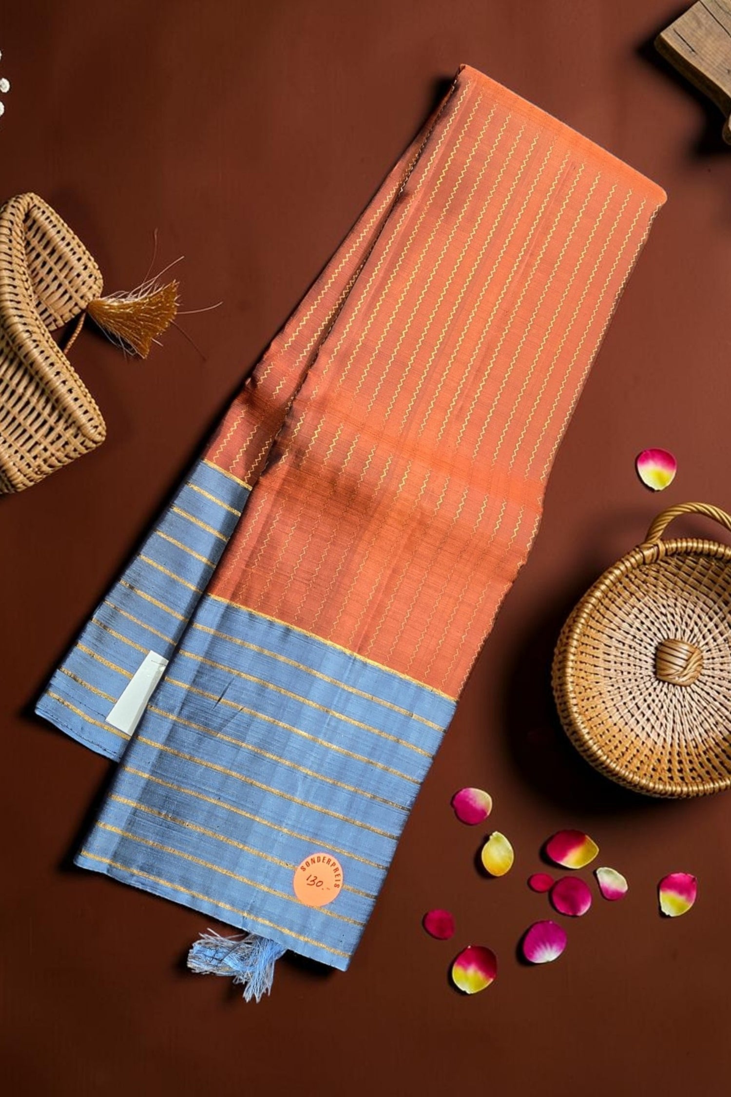 Saree with blue and orange pattern on a brown surface with decorative elements.