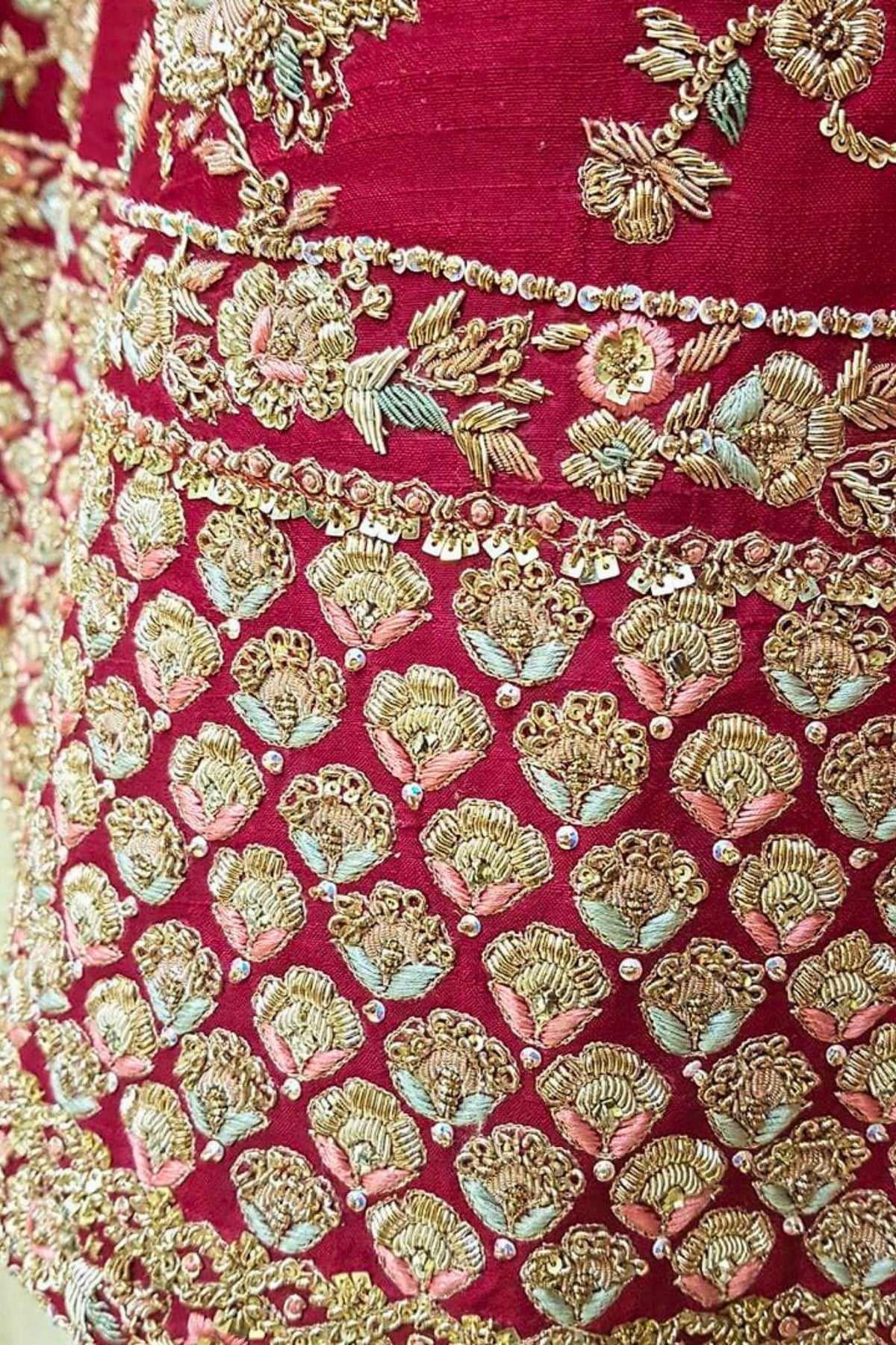 Close-up of a red fabric with gold and green floral embroidery
