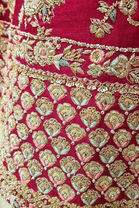 Close-up of a red fabric with gold and green floral embroidery