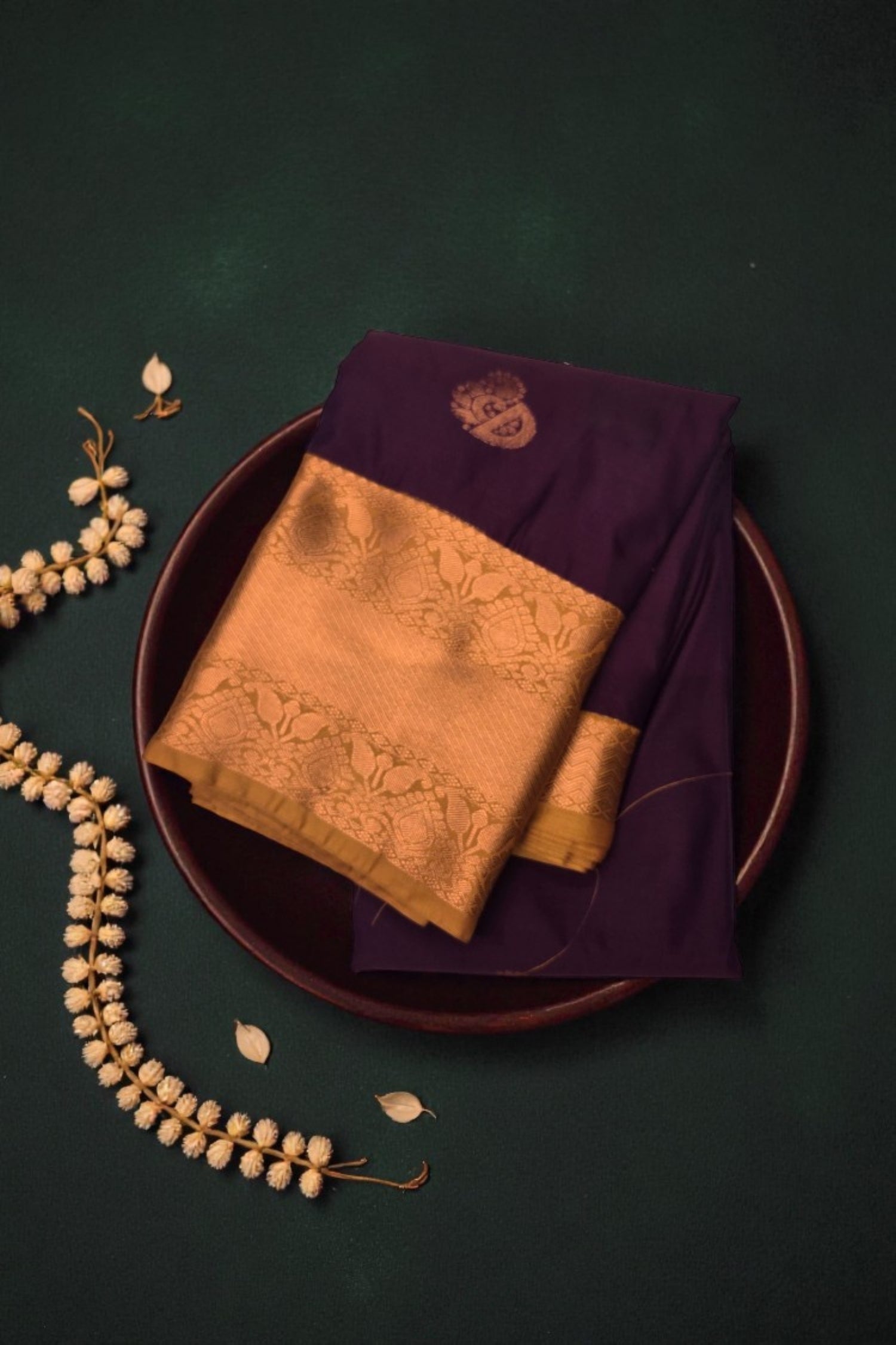 Purple and gold saree on a dark green background with decorative elements.