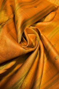 A close-up of draped golden-yellow fabric with woven geometric patterns and subtle green accents, arranged in soft folds.