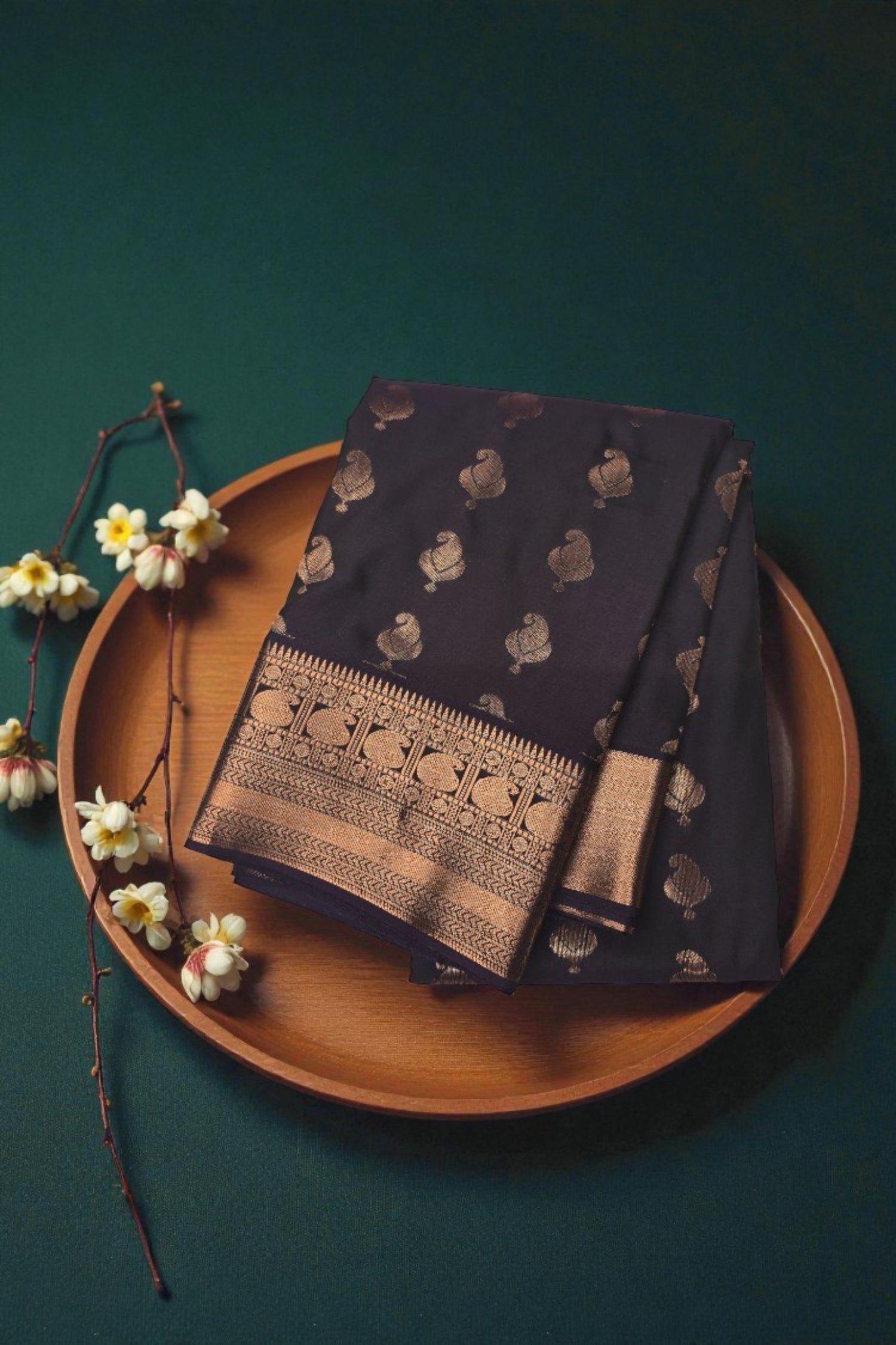 Navy blue fabric with gold patterns on a wooden plate against a dark green background