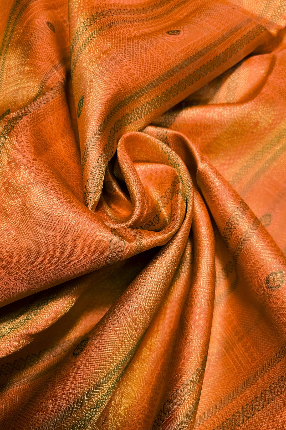 A close-up of draped orange fabric with a subtle woven pattern and a warm golden sheen.