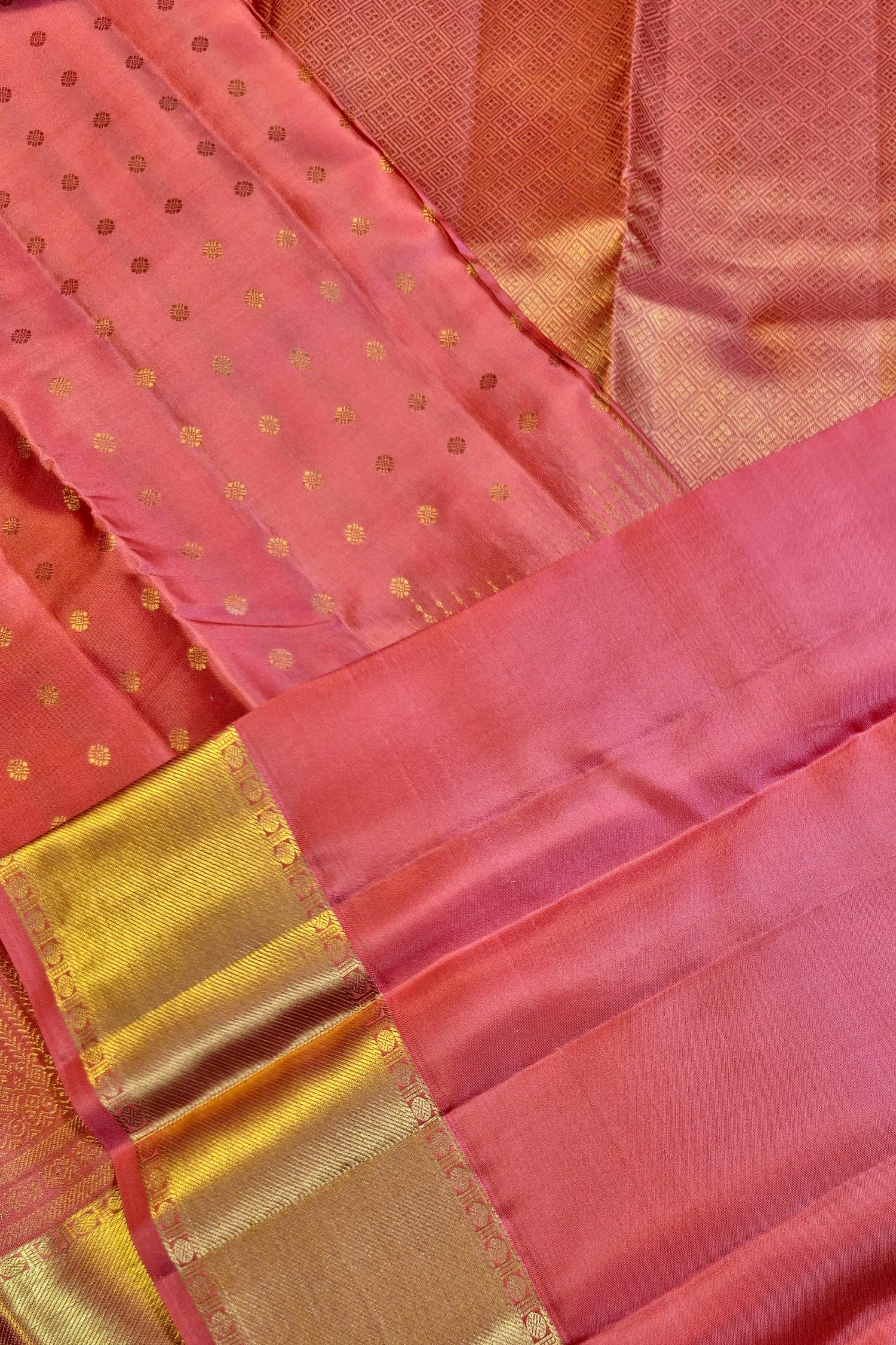 Peach pink silk saree with gold zari featuring intricate woven patterns and a wide gold border.