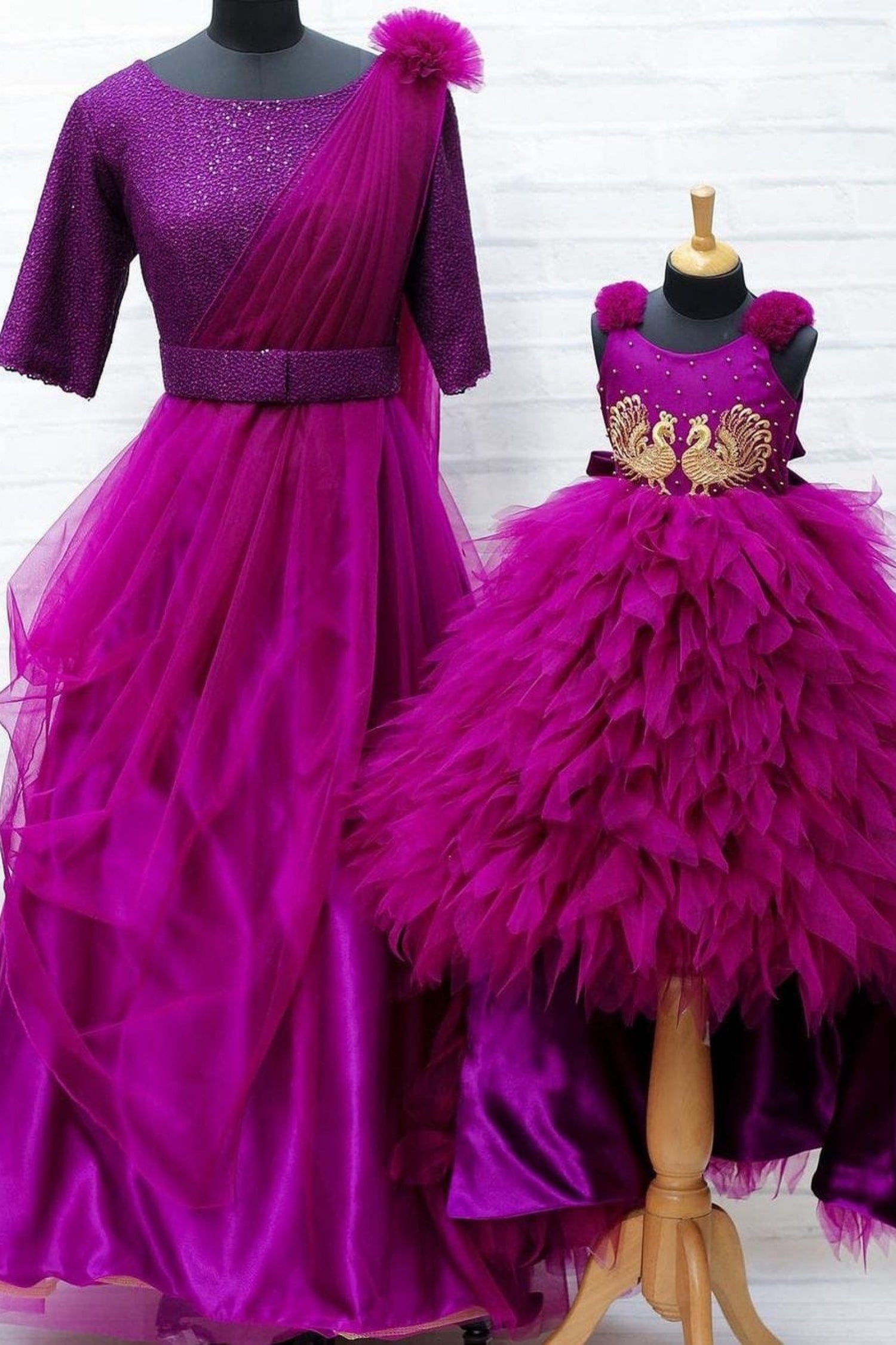 Purple evening gown and matching children's dress on mannequins against a white background
