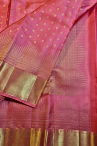 A close-up of a pink silk saree with gold zari woven patterns, featuring a dotted body, a wide gold border, and a detailed gold pallu.