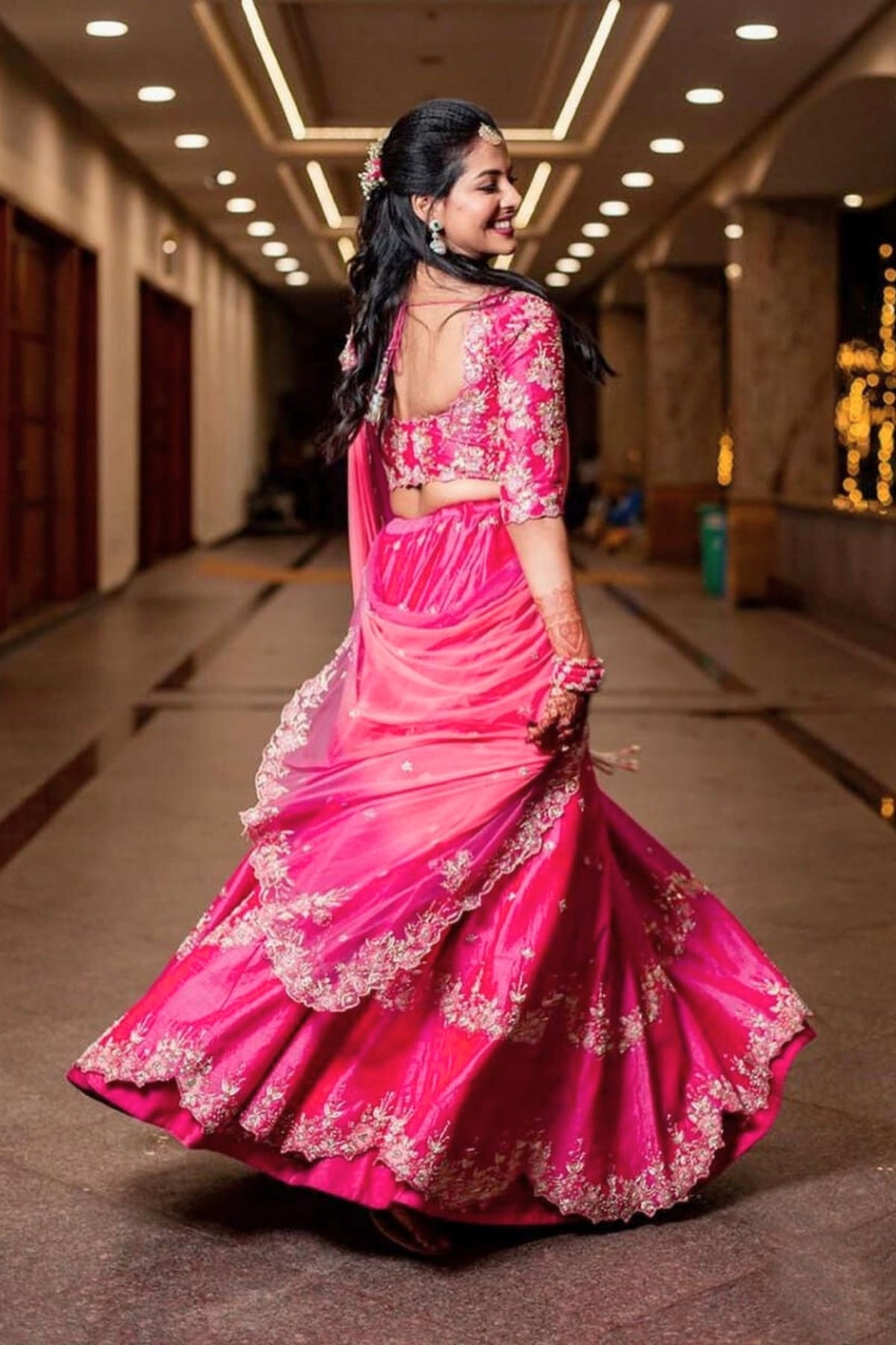 Woman in a pink traditional outfit with floral patterns in an indoor setting.