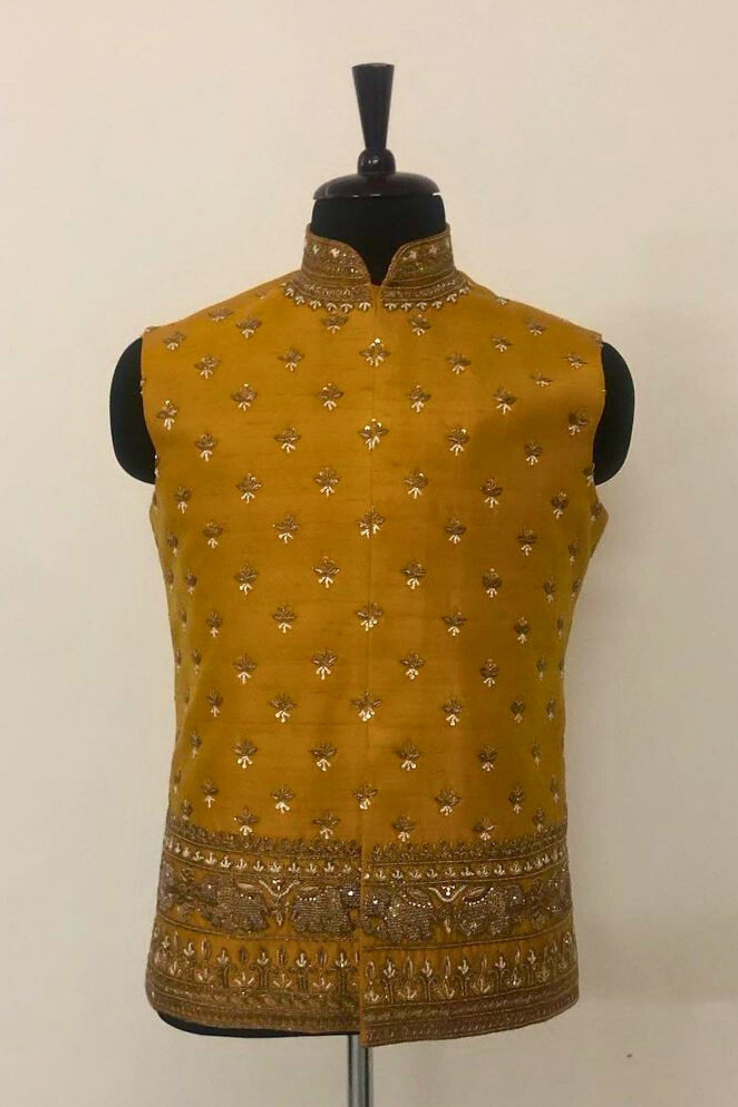 Mustard yellow embroidered vest on a mannequin against a plain background