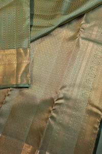 Close-up of a woven fabric textile with a sage green body, gold zari metallic patterns, and a matching green border with gold detailing.
