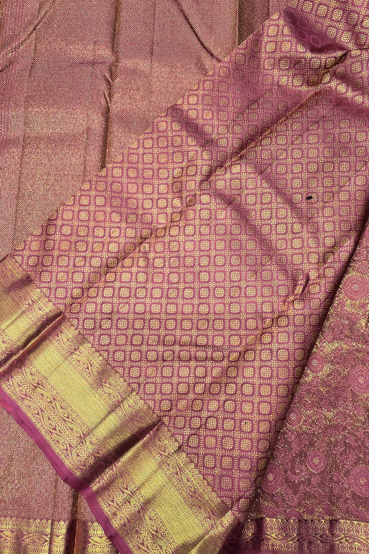 Close-up of a pink and gold patterned fabric with a textured surface.