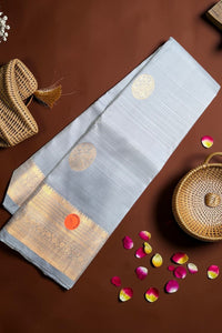 Light blue saree with gold patterns on a brown surface with wicker basket and rose petals.