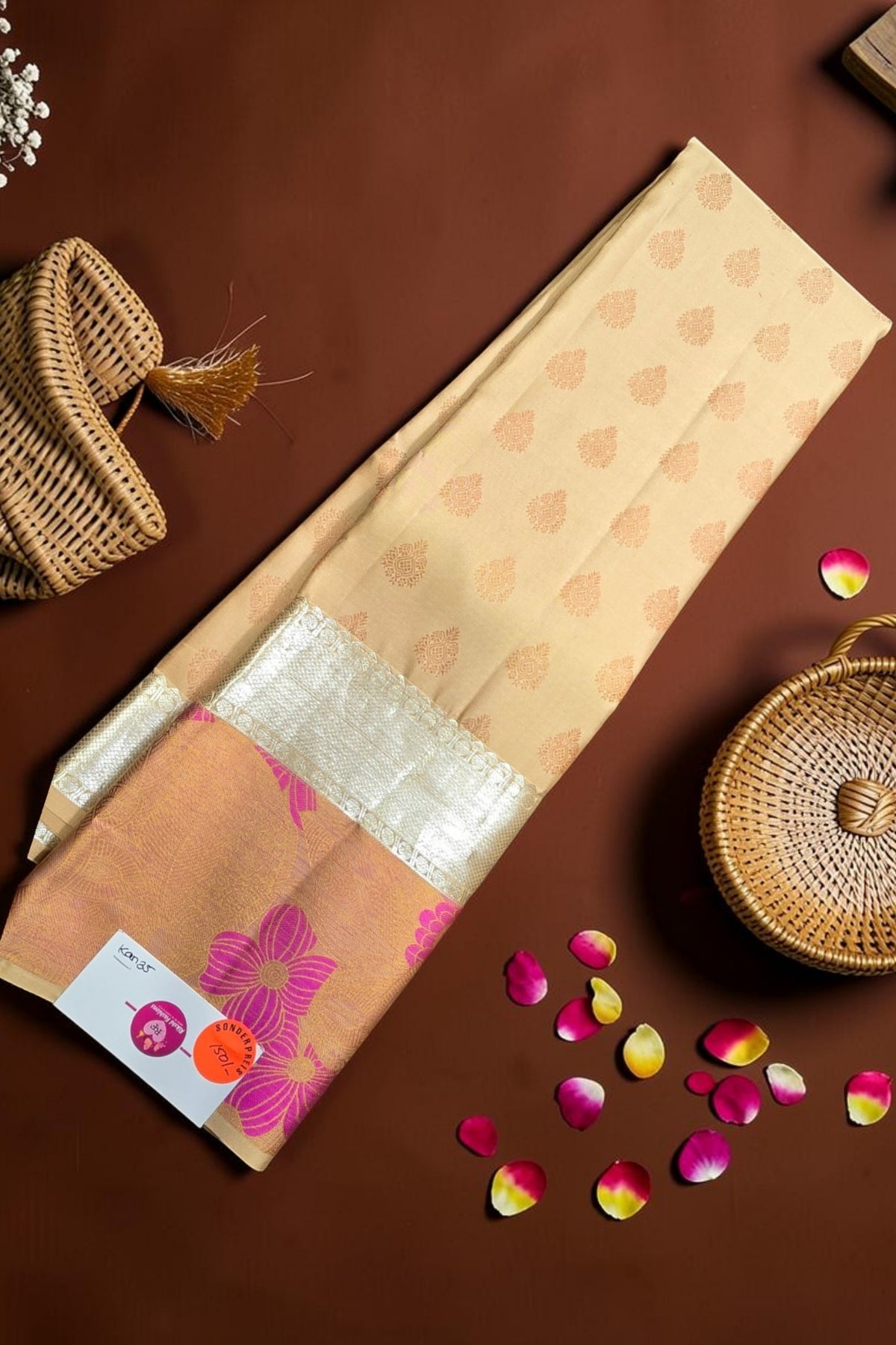 Beige fabric with floral patterns on a brown surface with wicker baskets and flower petals.