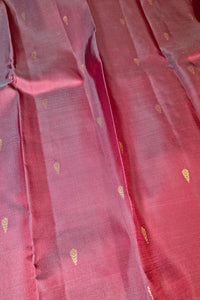 A close-up of a dusty rose pink fabric with small, scattered metallic gold woven motifs.