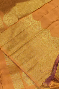 Close-up of a gold saree with intricate patterns on a brown background