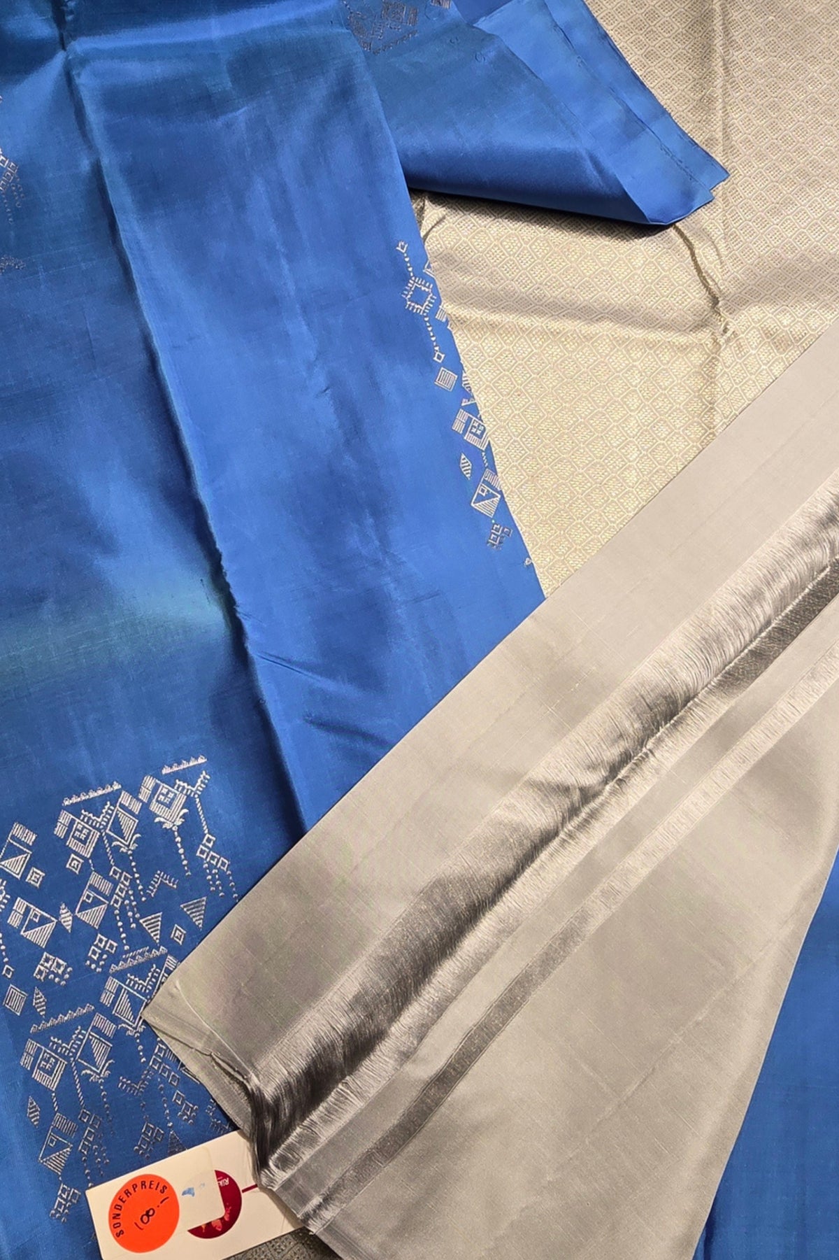 Close-up of blue and gray fabric with intricate patterns on a textured surface.