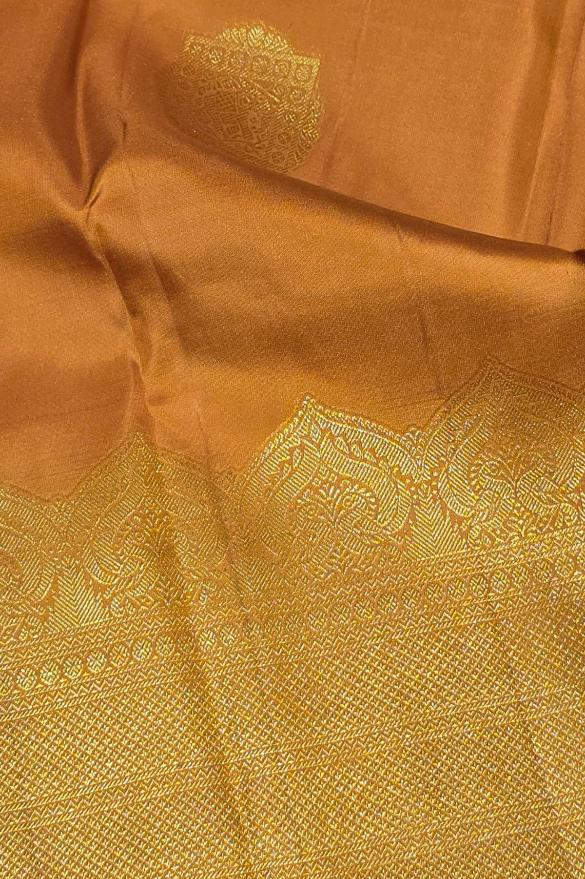 Close-up of a brown fabric with intricate gold embroidery