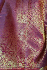 A close-up of a draped purple silk fabric with intricate gold zari woven patterns and borders.