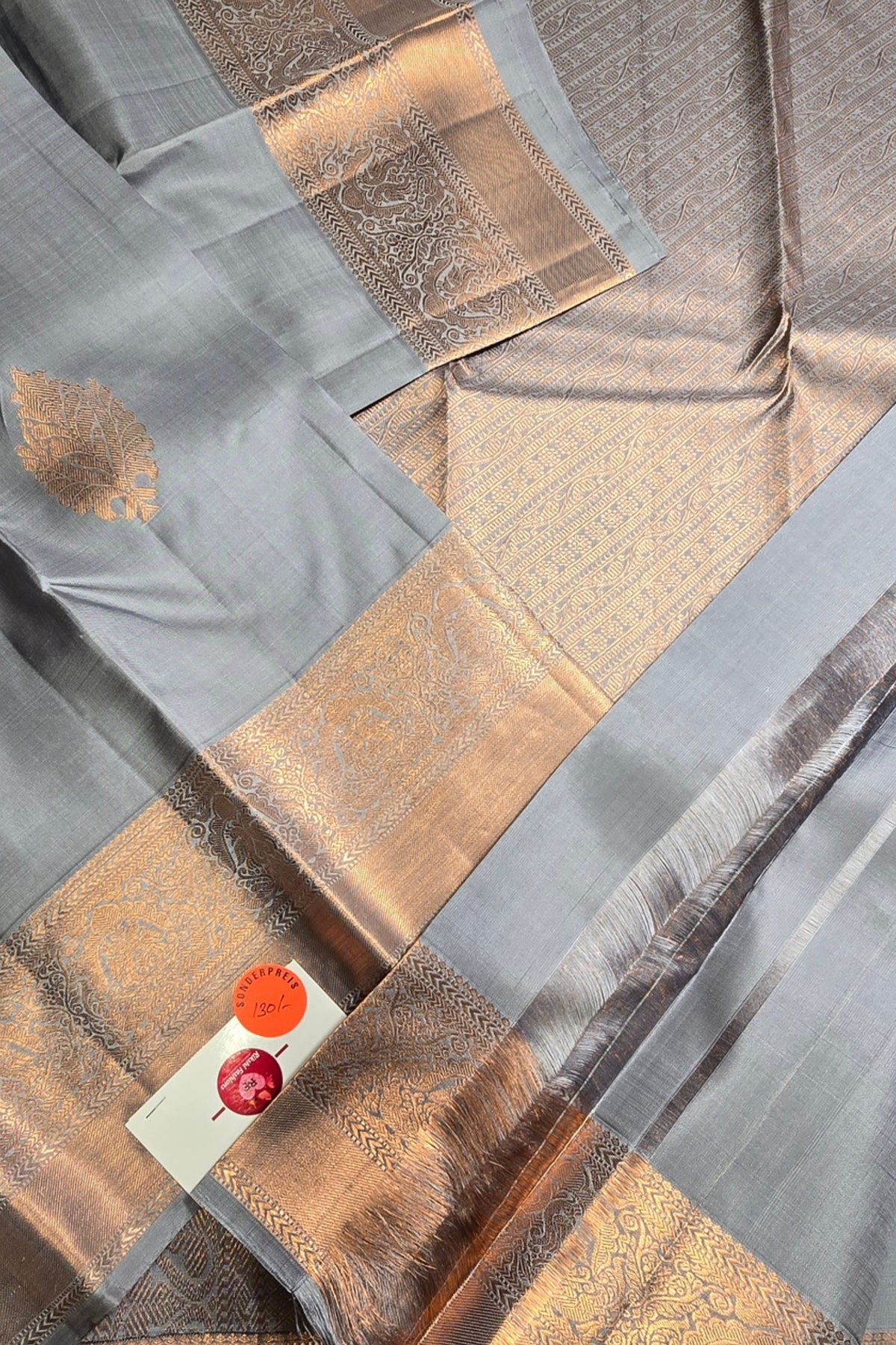 Close-up of a fabric with gold and gray patterns and a visible brand label.