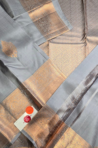Close-up of a fabric with gold and gray patterns and a visible brand label.